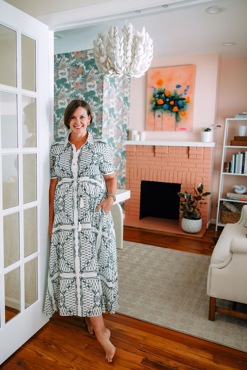 Jackie Barnes, interior designer standing in front of her desk with a cup of coffee.
