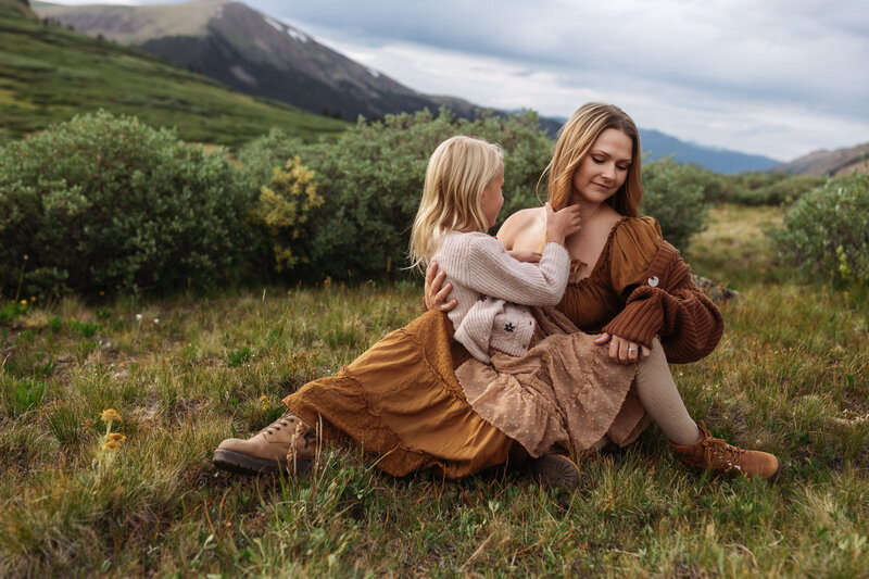 Daughter sitting on Mother's lap in the beautiful mountains of Colorado.