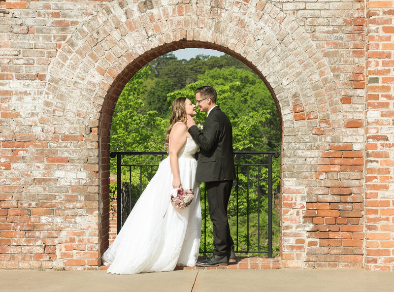 bride and groom smiling at each other with brick at The Bibb Mill  in Columbus Georgia by Columbus Georgia wedding photographer Amanda Richardson Photography