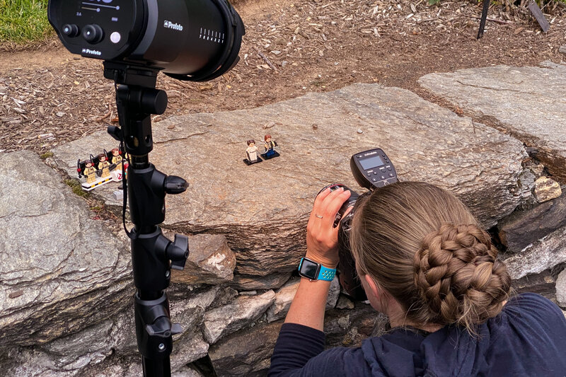 Jen Stitt setting up a creative macro shot of an engagement ring paired with Lego mini-figures, crafting a fun and unique detail photo during an engagement session.