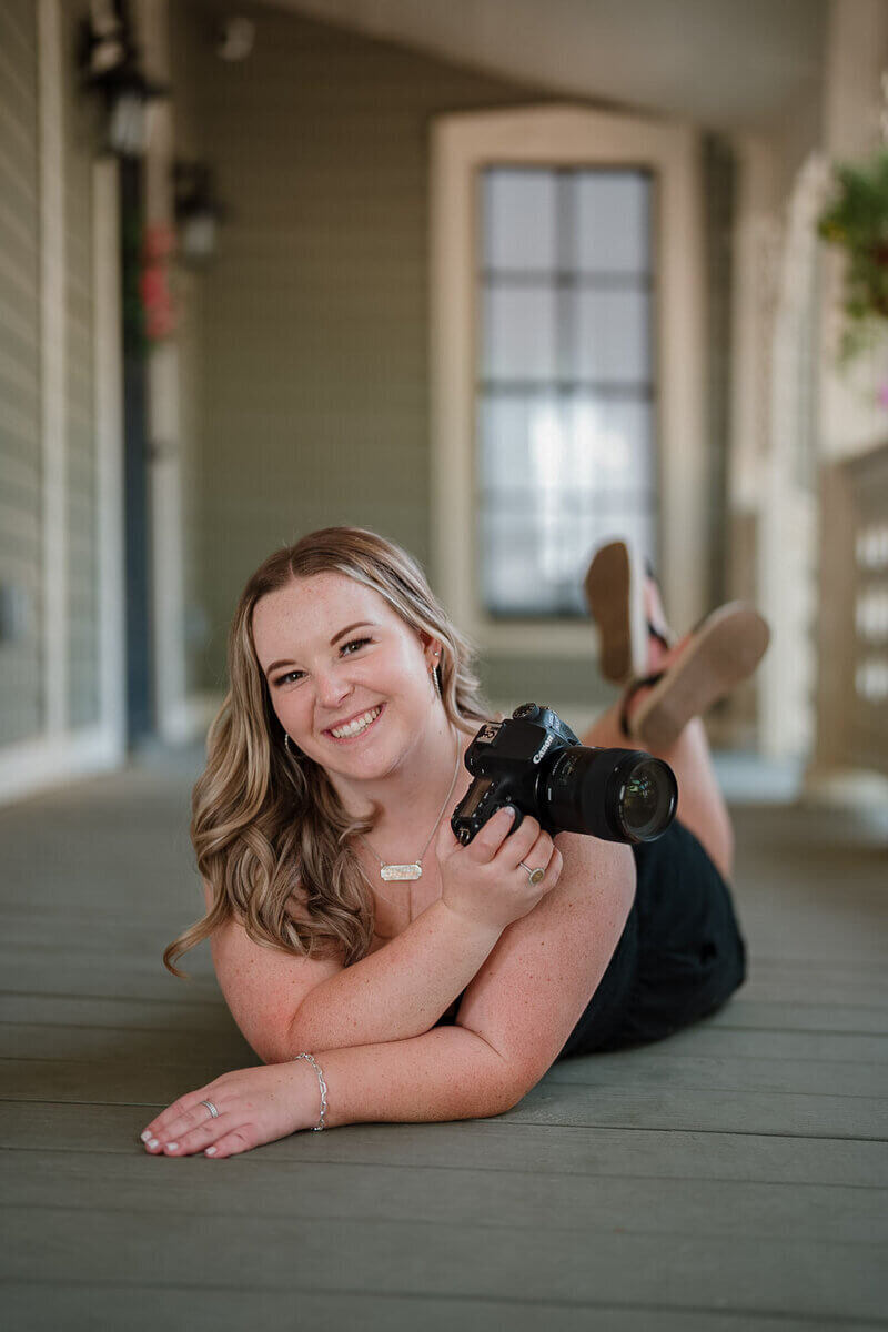 Hannah laying on floor posing with her camera