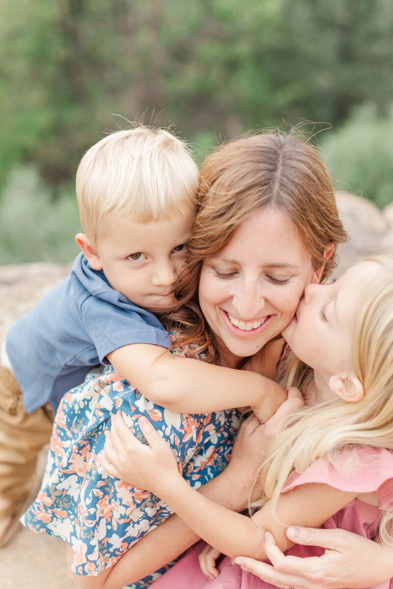 mom with kids and daughter is kissing moms cheek in morrison colorado