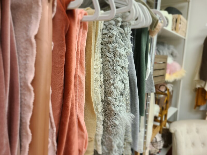 Fabrics on velvet hangers hanging up in order of color