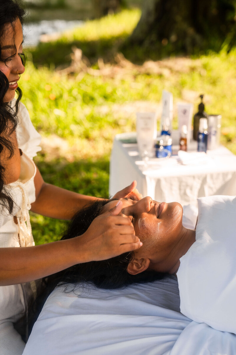 Woman putting lotion on her clients face
