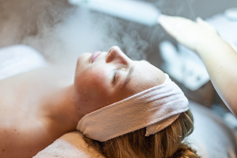 Rachel Smith giving facial to client with steam wearing towel headband.