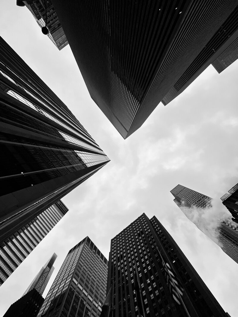 Looking up at skyscrapers, symbolizing organizational growth and enrichment through team facilitation and training.