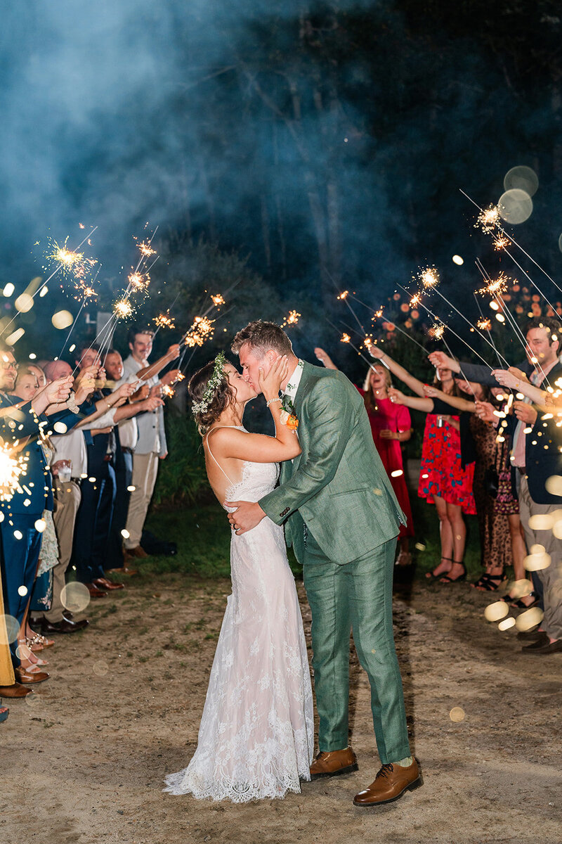 A couple shares a kiss in the dark with family and friends around them during their Maine elopement. 