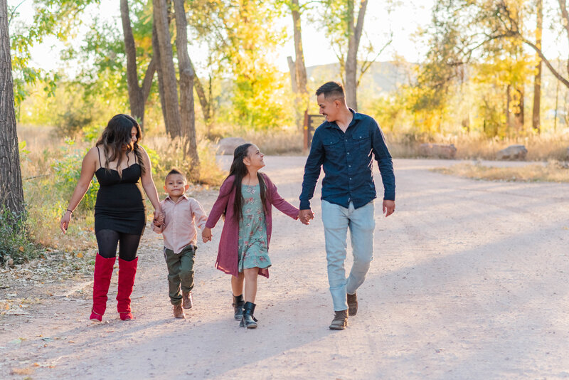 A family walks hand-in-hand through a park by Laramee Love Photography