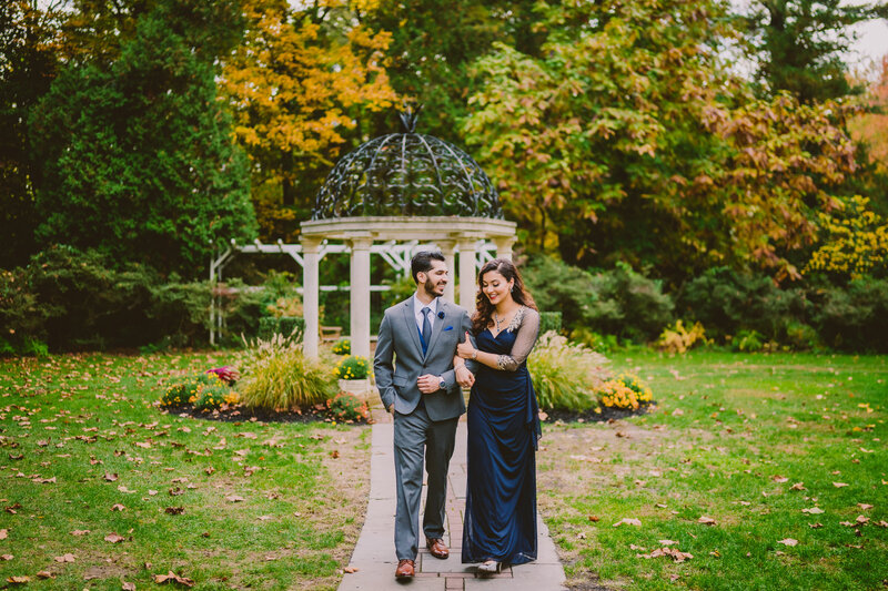 A couple walking in front of a gazebo at the sayen gardens in nj