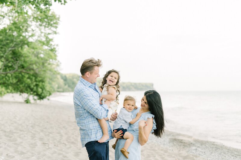 Family of four smiling for photography session at Milwaukee beach, taken by Milwaukee photographer Abby Park Photography
