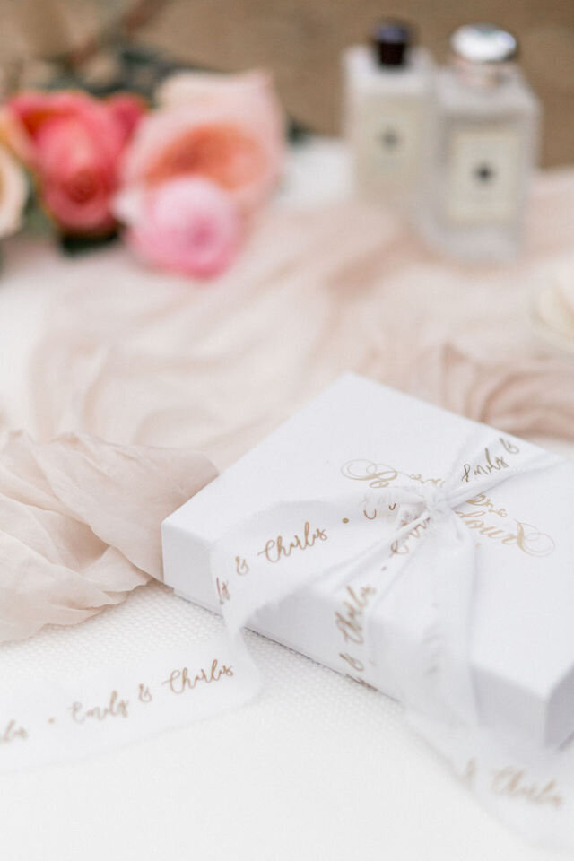 A gift box tied with personalised ribbon with the bride and grooms name on