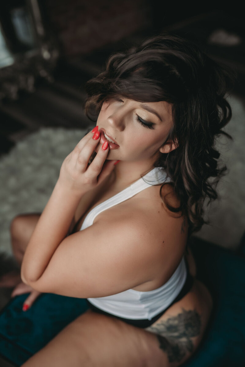 boudoir portrait of brunette woman touching lips with red nails boudoir