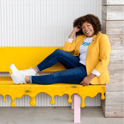 Photo of Michelle McKown-Campbell  smiling  on a yellow bench