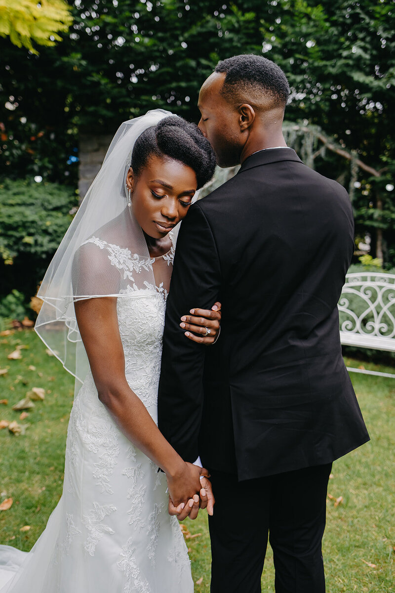 Tender post-ceremony moment between an African bride and groom in a peaceful hotel garden in Dublin, capturing their deep connection
