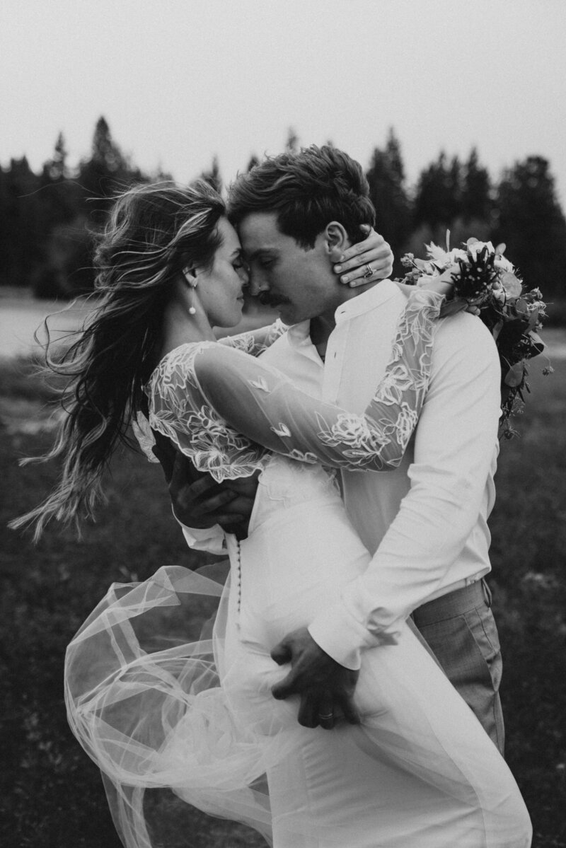 Black and white image of intimate moment between bride and groom with hair and dress blowing in the wind groom grabs brides butt by California elopement photographer Kasey Mantiply