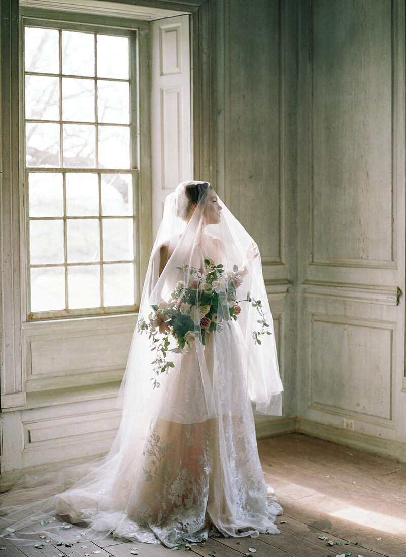 Bride with veil over face looking out window