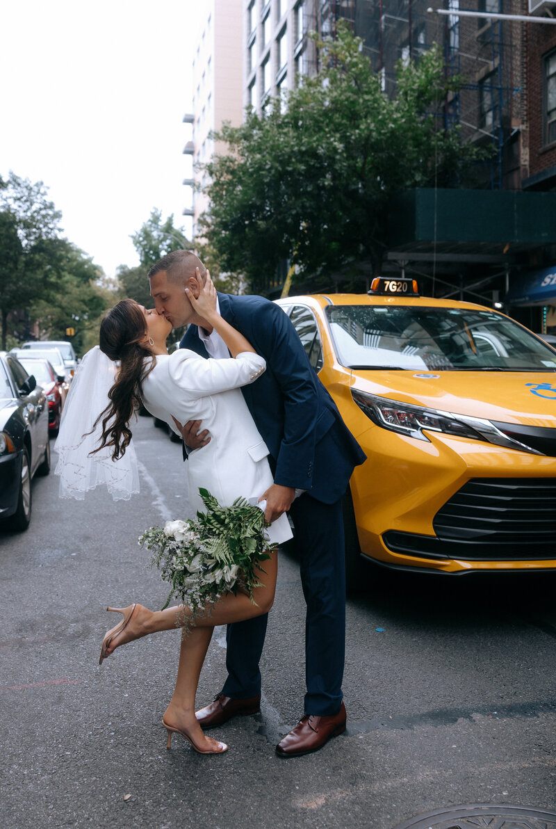 Couple standing together by yellow cab City Hall during their NYC elopement