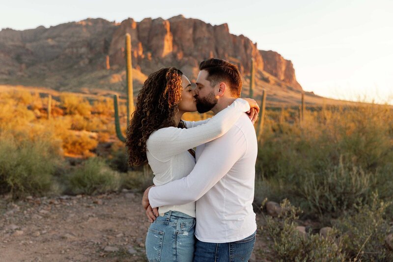 Couple kiss in the soft glow of sunset in the Phoenix desert.