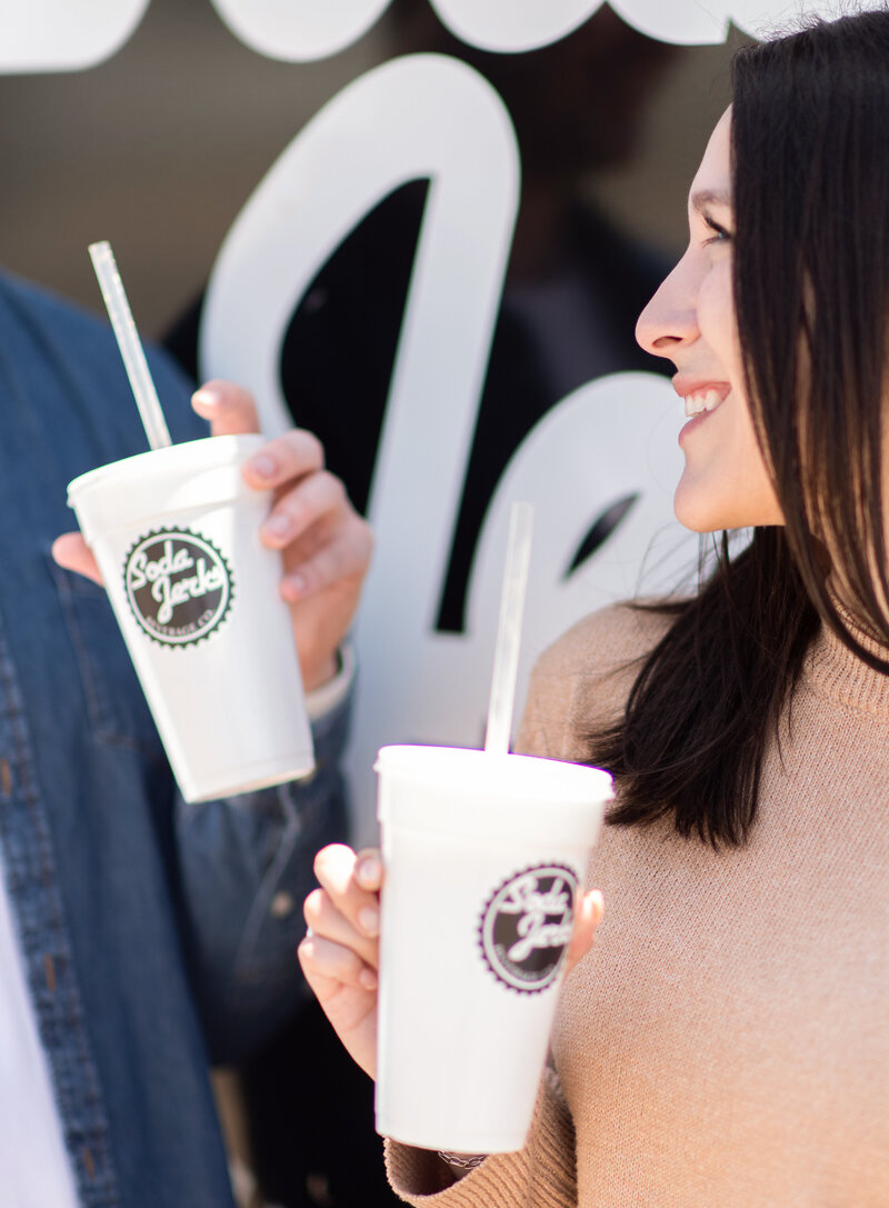 Two people pose with a food truck drink in their hand for a branding image