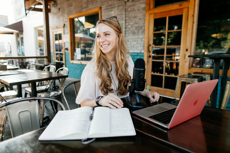 woman sitting at table with laptop and notebook