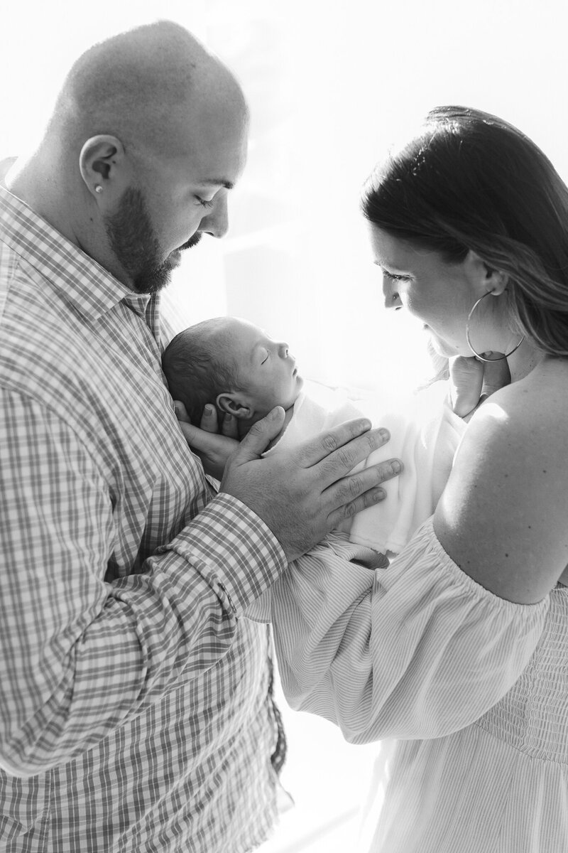 mom and dad hold newborn in between them