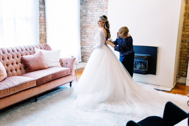 mom helping the bride with her dress at Aster Weddings and Events