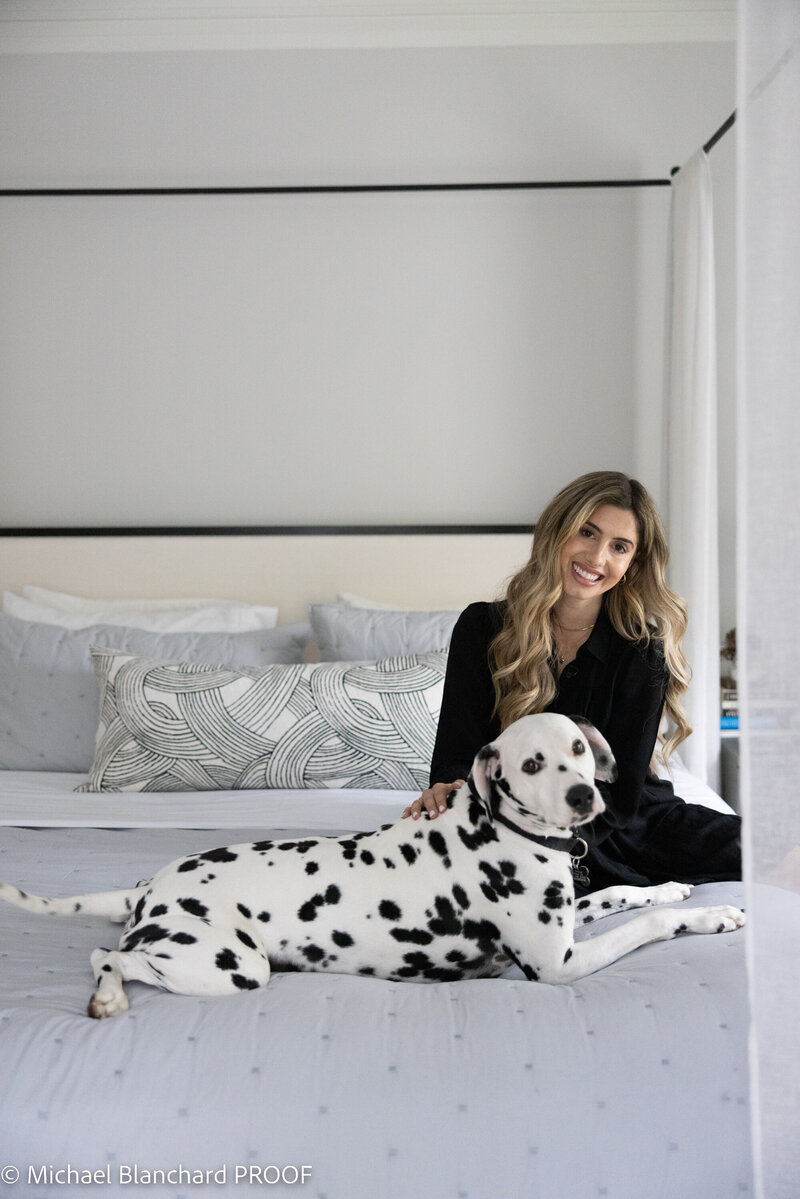 Tiffany Barqawi, Boston interior designer, in a modern bedroom with a Dalmatian and layered neutral textures