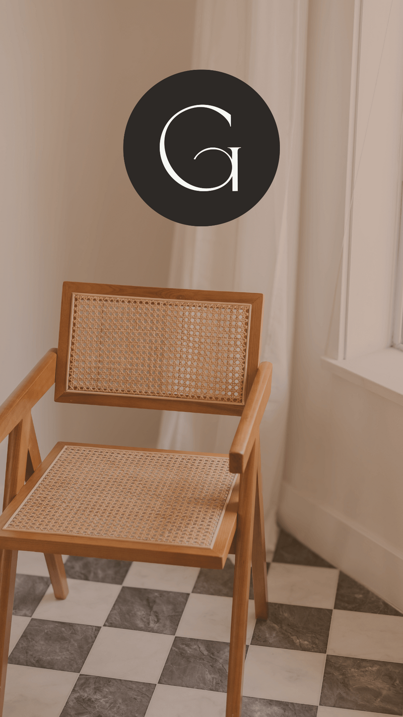 A wooden chair with a woven seat and backrest sits on a black-and-white checkered floor, near a white curtained window—an elegant touch perfect for a hair salon website design. Above the chair is a black circle with a white letter G.