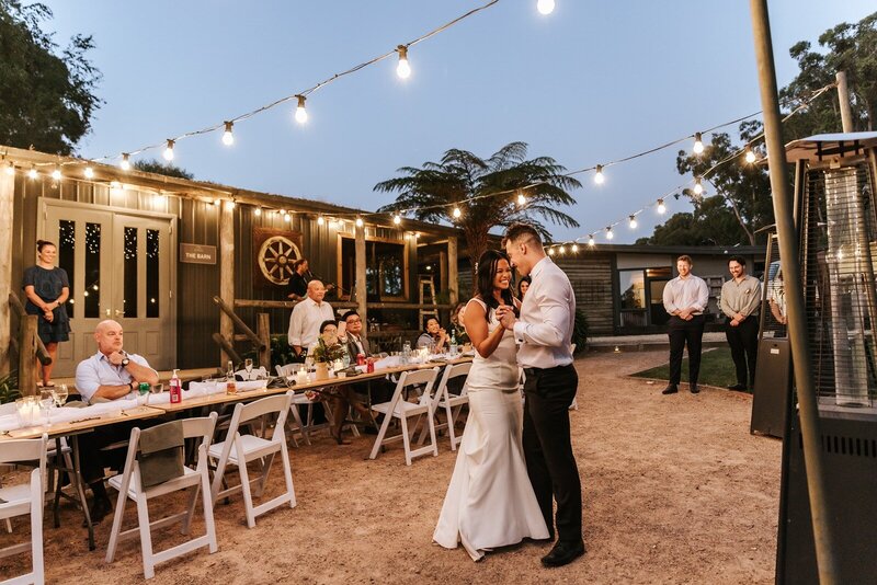 A bride and a groom standing on sand in front of a rocky cliff face