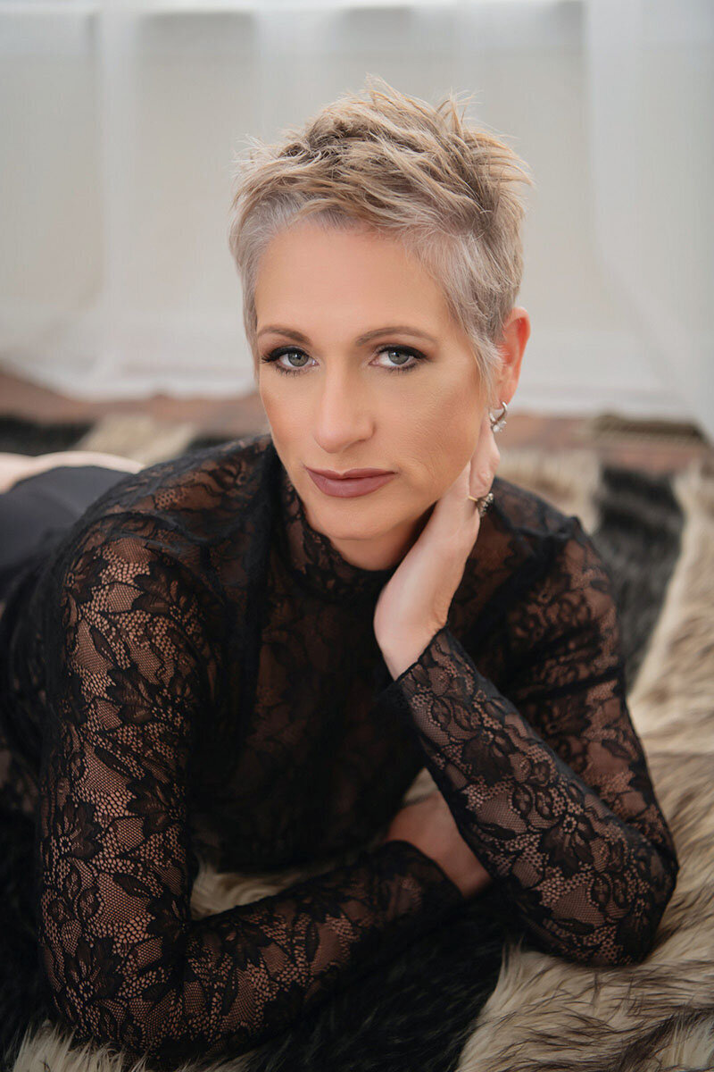 Blonde woman posing in gold accented boudoir photoshoot