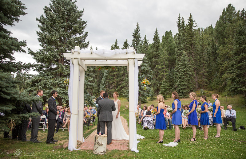 Wedding ceremony in outdoor mountain meadow at Mountain View Ranch with white arbor
