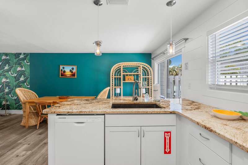 Open kitchen with tropical wallpaper view and rattan dining area, ideal for guests booking Santa Rosa Beach or VRBO Panama City listings.