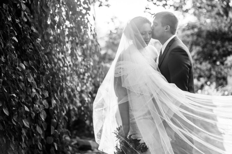 bride and groom kissing while she wears her custom pearl bridal veil
