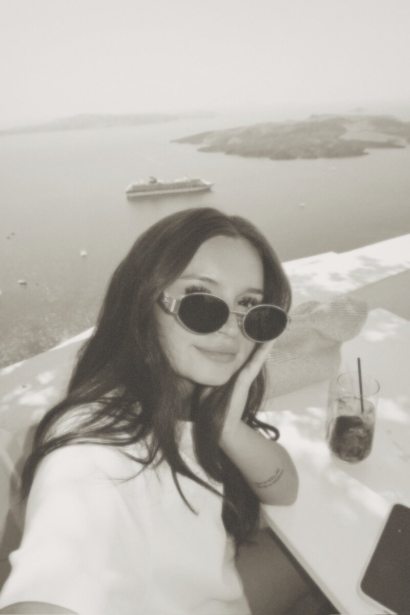 The founder of Studio Petita, Chloe, in a Greek Cafe with the sea in the distance
