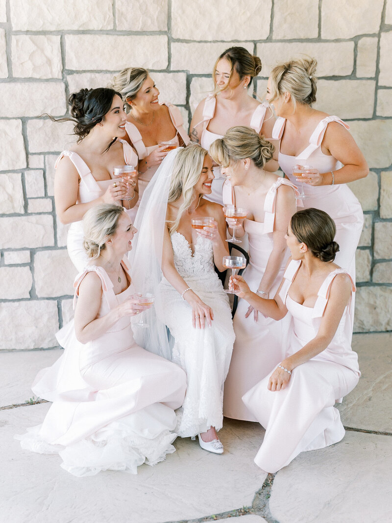  bridesmaids, laughing at chateau Noland a wedding venue in San Luis Obispo, wearing all pink dresses and toasting champagne during a fun candid moment