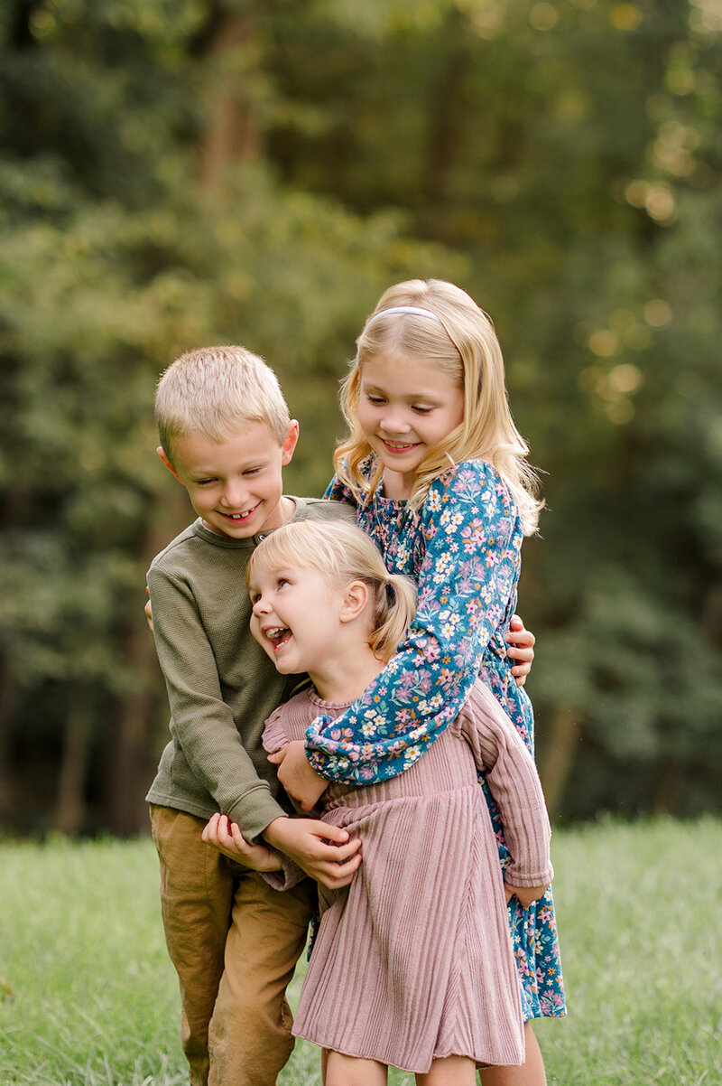 three siblings hugging at home laughing during lancaster pa family session