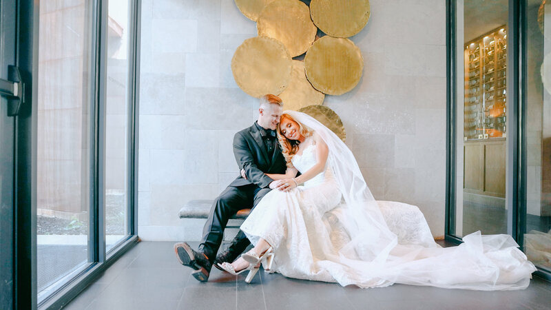 Bride and groom snuggling sitting in front of gold decoration hallway promontory club, Park City Utah taken by Cali Warner Media