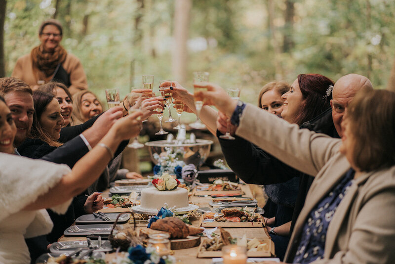 Wedding guests toasting in the forest during microwedding in Scandinavia on Bornholm island