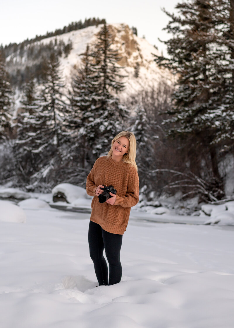 Photographer Alex Celani holding her camera in the mountains by beaver creek colorado