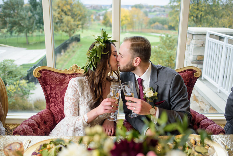 Bride and Groom toasting to a kiss  at their luxury  sweet heart table