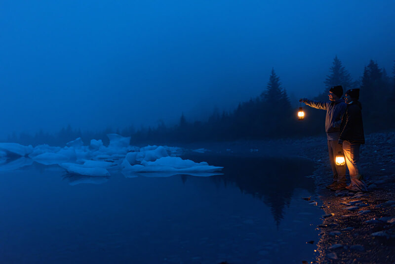 It is dark out, and the couple who was just married that day stands next to Bear Lake holding lanterns glowing with warm light.  They are shiloutted in the dark blue sky, and the icebergs in the lake glow white in the dark. 