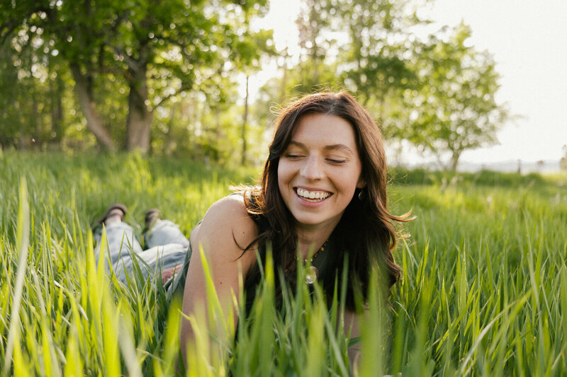Image of a woman smiling laying in a green grassy field