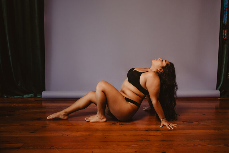 A person in lingerie sitting on the ground and leaning back on their hands 
