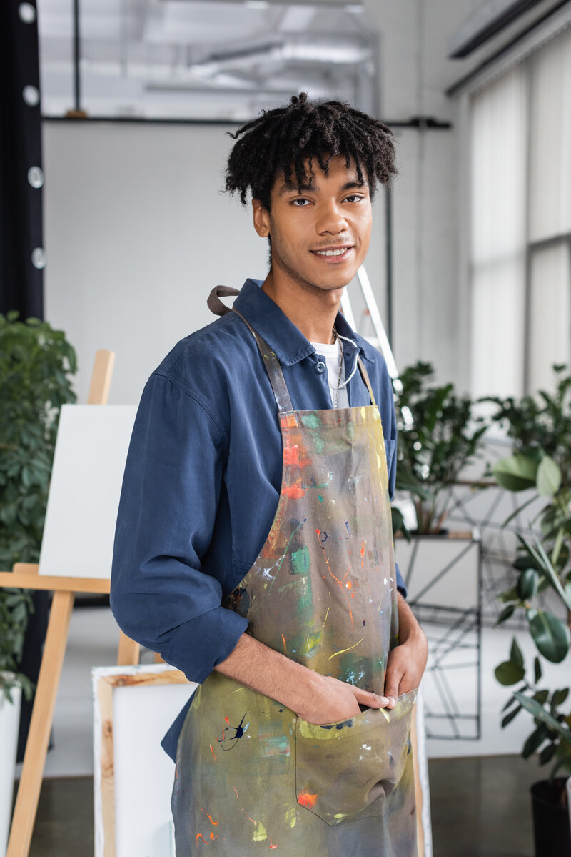 young-african-american-artist-in-dirty-apron-posin-2023-11-27-05-05-28-utc