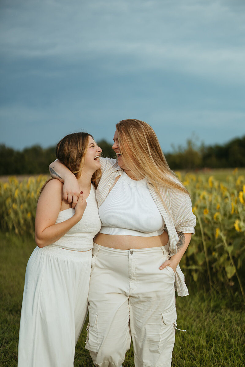 women laughing and walking together in sunflower field