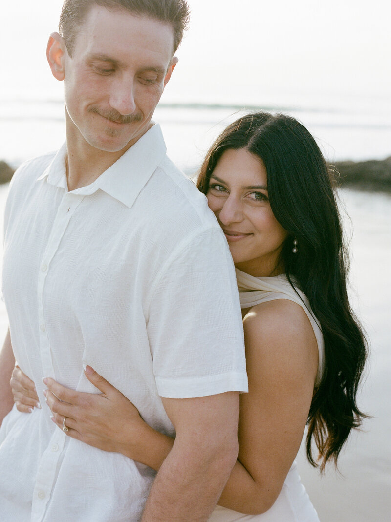 woman hugging her fiancee from behind on the beach in Orange County on medium format film