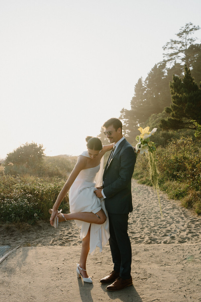 A couple walks on the beach at sunset after their Oregon Coast wedding ceremony. 