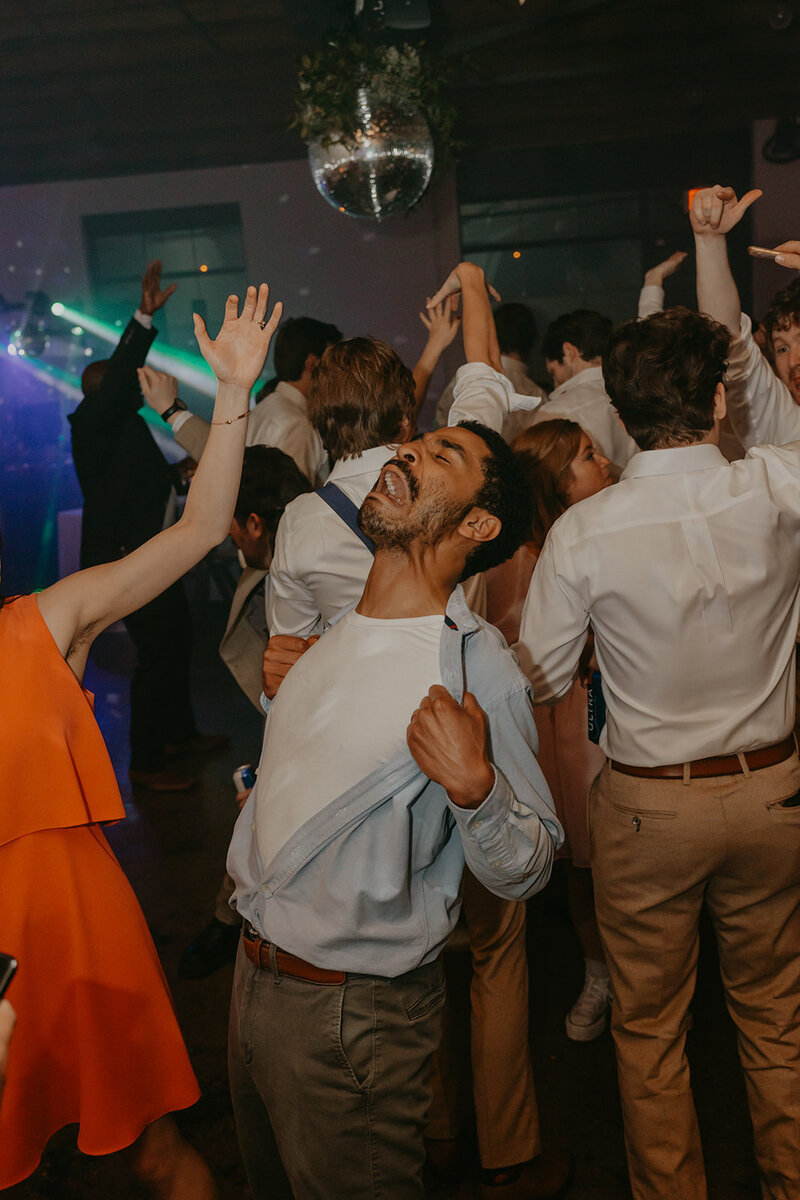 man rips shirt on wedding dance floor