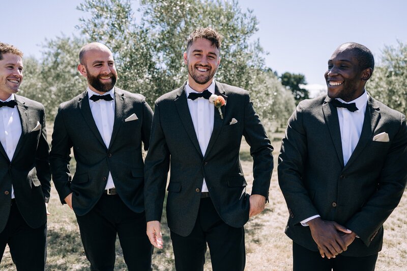 groom and groomsmen in matching black suits with white shirts and black bowties a very classic elegant style