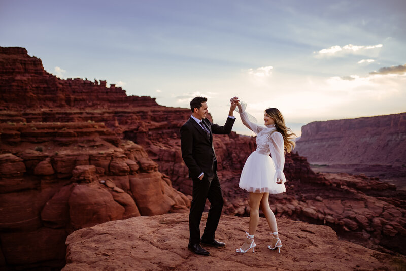 Couple embracing at sunset in a desert landscape, highlighting adventurous elopements by an Oregon Coast Elopement and Wedding Photographer.
